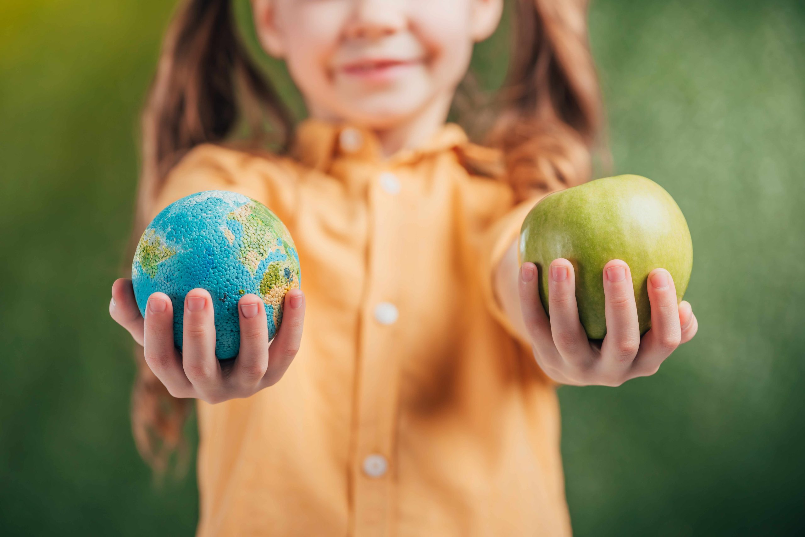 Selective Focus Of Child Holding Globe Model And Apple On Blurre