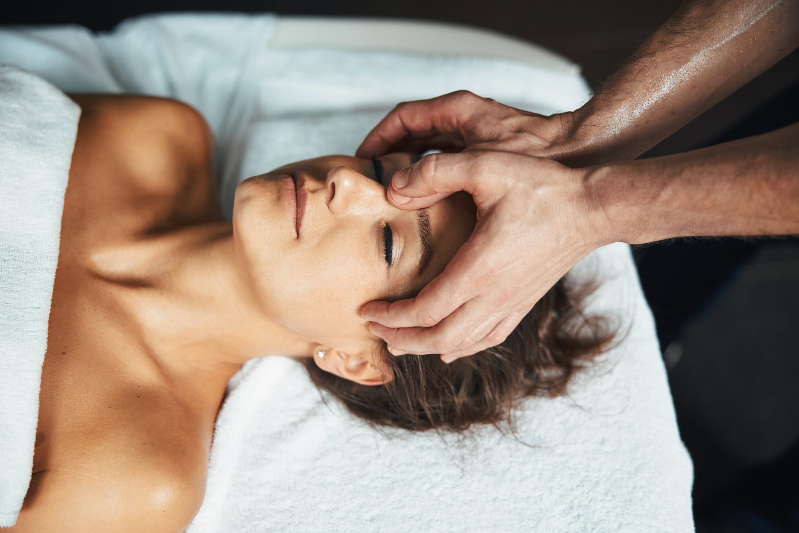 Adorable Caucasian Woman Lying On Massage Table While Getting Relax Massage On Head In Wellnees Center