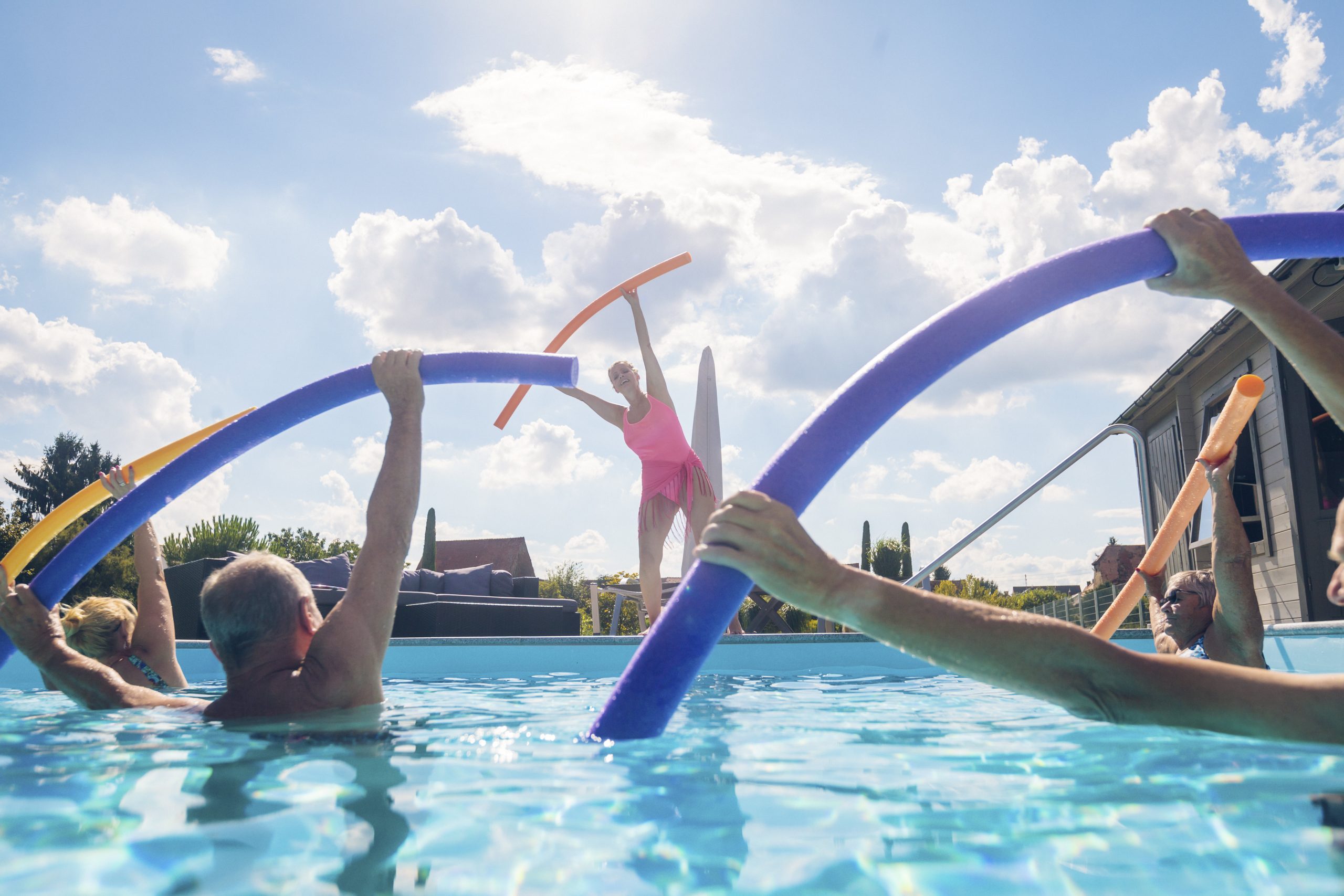 Group Of Seniors With Trainer Doing Water Gymnastics In Pool