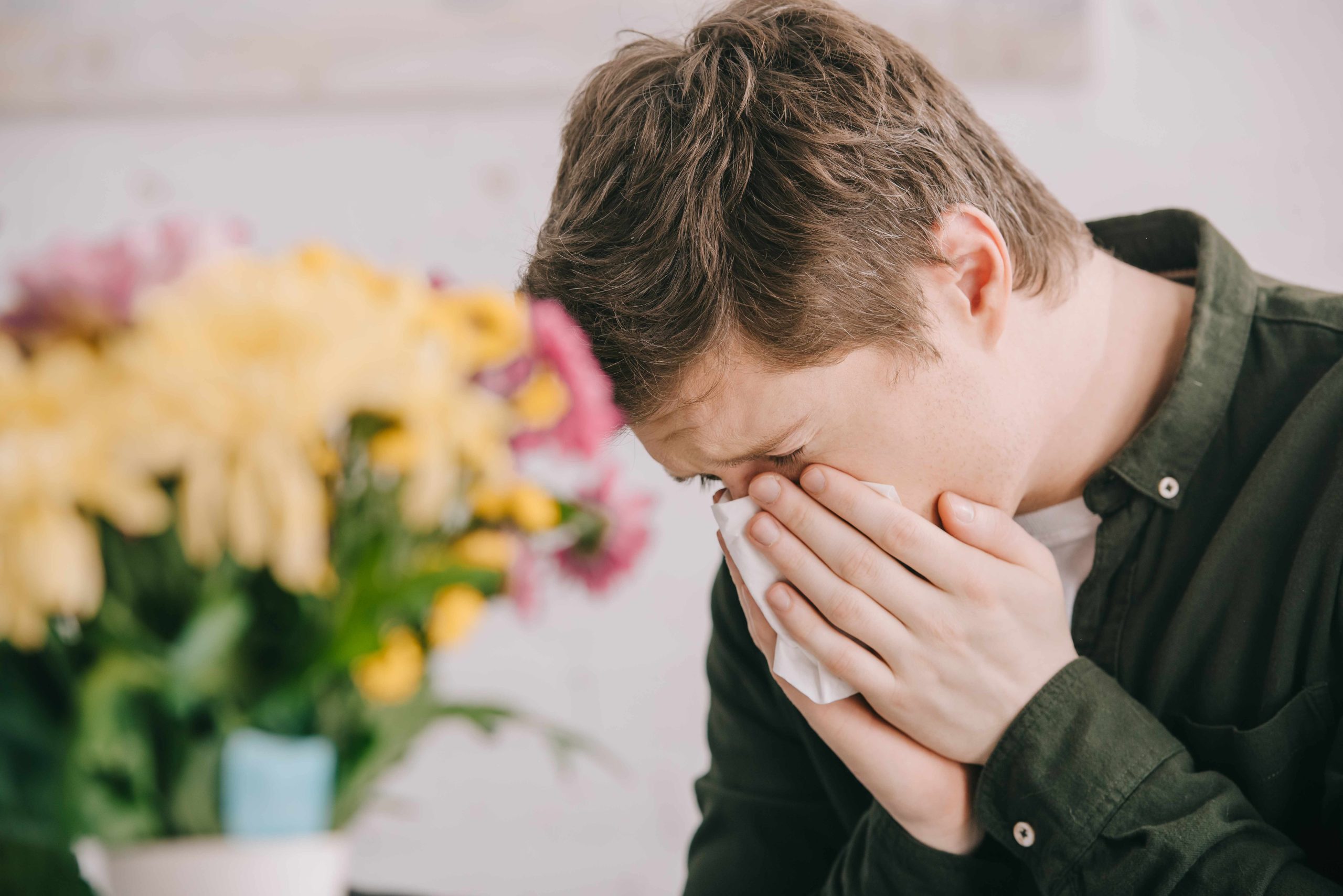 Selective Focus Of Sneezing Man With Pollen Allergy Near Bloomin