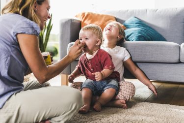 Mother Feeding Kids In Living Room